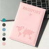 Pinkes schlankes Kunstleder-Reisepass-Cover mit erhabenem Weltkarten-Design neben einer Laptop-Tastatur.