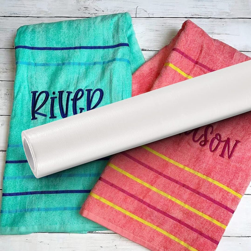 A roll of water soluble embroidery stabilizer film with pink and teal stripes is displayed on a white wooden surface.