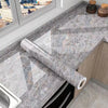A close-up view of a gray marble effect self-adhesive PVC film being applied to a kitchen countertop.
