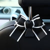 Black bow-shaped car seat back hook with white trim and storage feature.