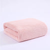 A folded, light pink plush velvet bath towel with a textured knit pattern.