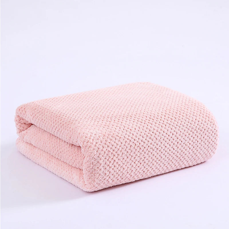 A folded, light pink plush velvet bath towel with a textured knit pattern.