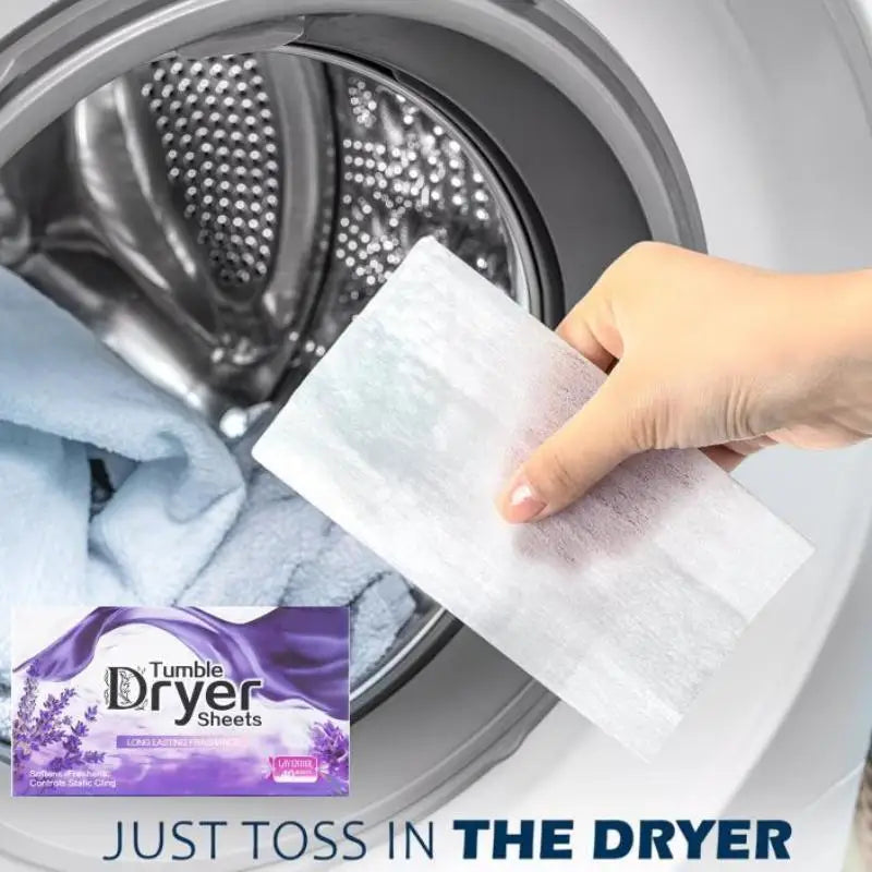 A hand is placing a white dryer sheet into the interior of a washing machine drum.