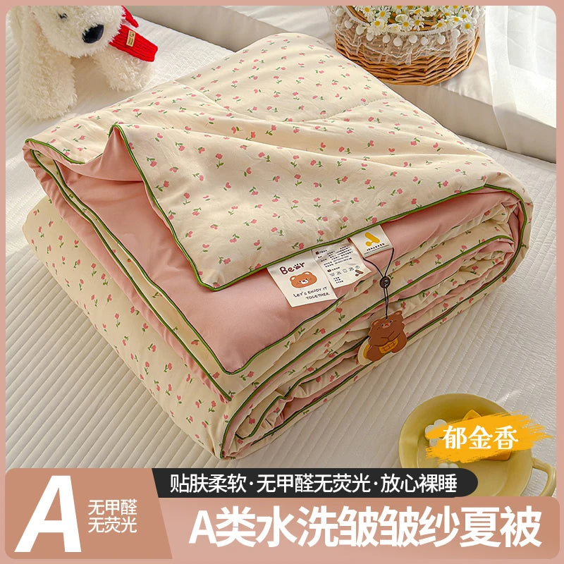 A lightweight summer quilt with a playful cartoon print featuring pink and cream colors.