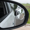 Close-up view of a side-view car mirror with a chrome blind spot mirror reflecting the vehicle.