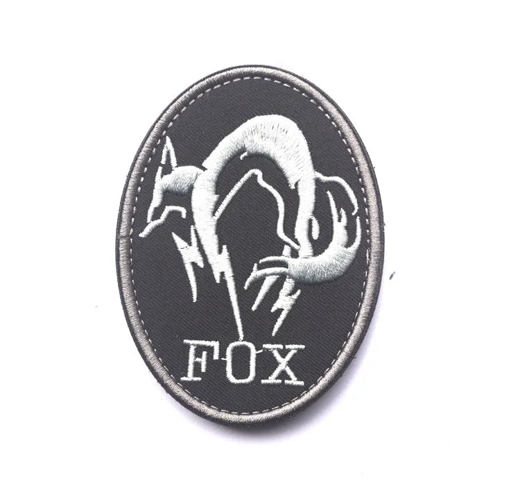 Black embroidered patch featuring a silver fox head design with lightning bolts and the word FOX.