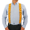 A man wearing a light blue shirt and black pants with bright orange elastic suspenders.