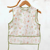 A sleeveless, waterproof baby feeding bib with a pale pink and green floral pattern featuring rabbits and strawberries.