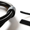 A close-up of a black nylon cable tie with an adjustable hook and loop fastener, showing the textured material.