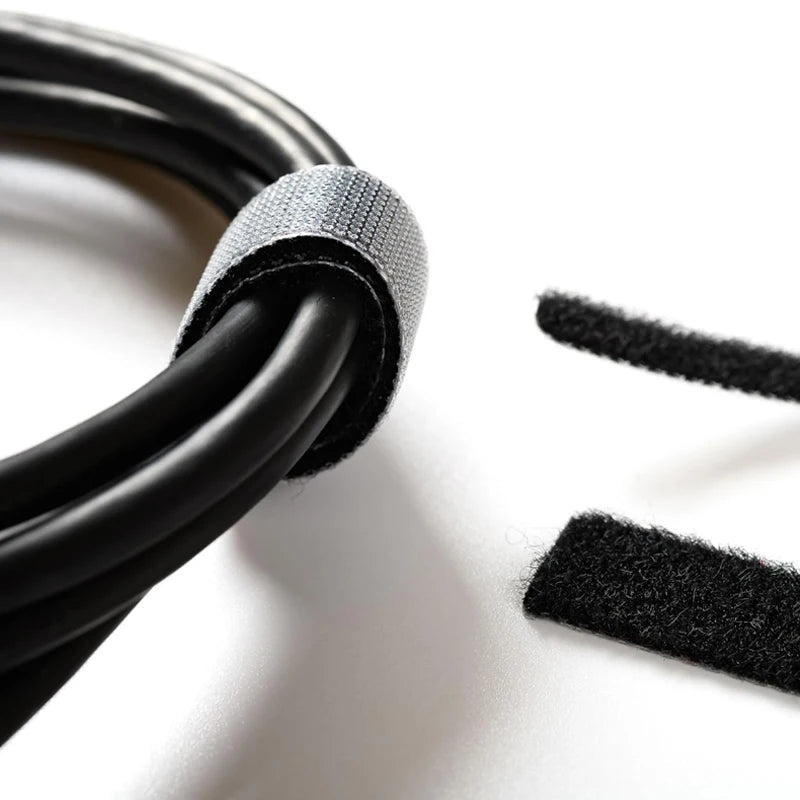 A close-up of a black nylon cable tie with an adjustable hook and loop fastener, showing the textured material.