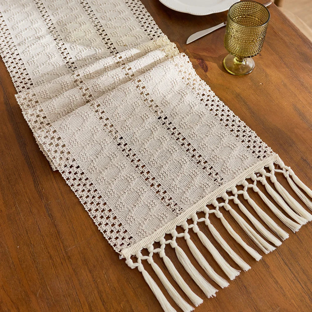 Beige boho table runner with tassels, hand-woven farmhouse style, displayed on a wooden table.