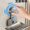 A hand is pressing a blue suction cup mechanism onto a stainless steel wall-mounted soap dish with a drain.