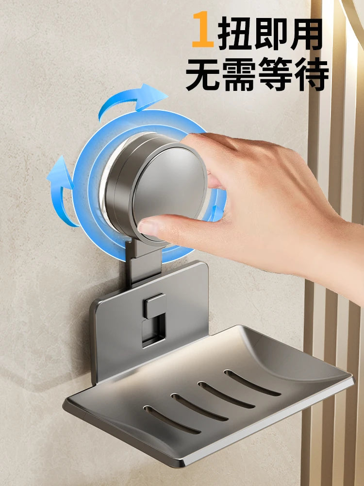 A hand is pressing a blue suction cup mechanism onto a stainless steel wall-mounted soap dish with a drain.