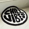 A round black and white letter carpet with the text SKILL VIBES embroidered in black.