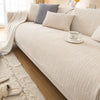 A beige sofa with light neutral cushions and a white mug on the armrest.