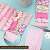 A collection of pink cotton quilted fabric strips in various patterns and colors are laid out on a light blue surface.