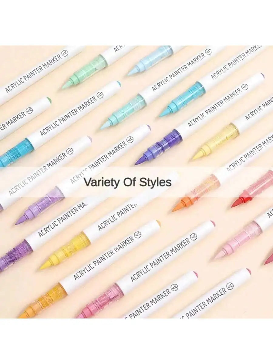 A variety of acrylic paint marker pens in different colors and fine tips arranged diagonally on a light background.