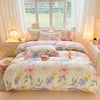 Rosa und weiße Blumen-Duvetcover mit lavendel-, gelben und blauen Blumen auf einem Bett.