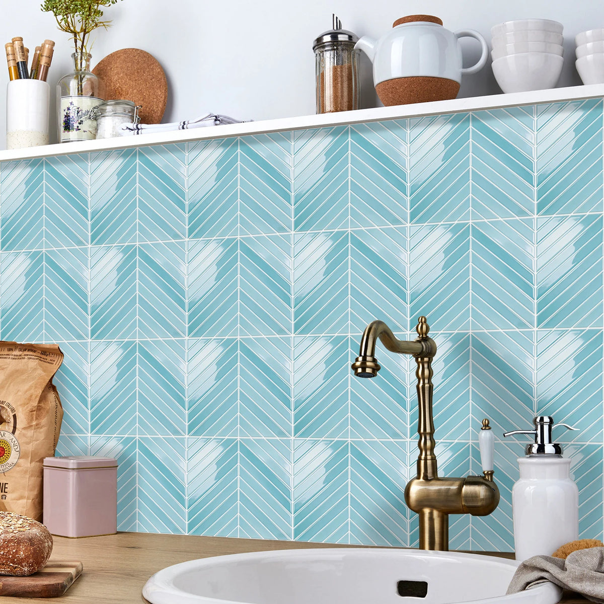 A bathroom featuring light blue herringbone marble peel-and-stick tiles on the wall and a brass faucet.