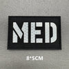 Black woven patch with white letters MED on a gray background