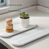 A white diatomite stone tray holds a succulent plant and a wooden brush on a countertop.