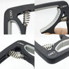 Close-up view of a black adjustable guitar capo with a silver spring mechanism and bridge pin puller.