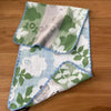 A folded pure cotton embroidered cartoon face towel featuring green and white floral patterns.
