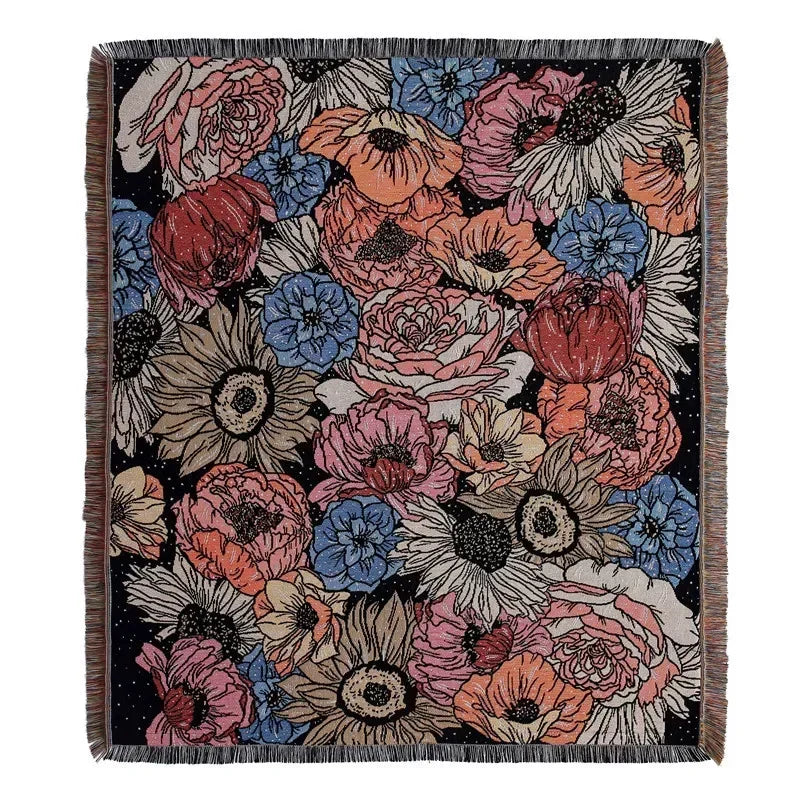 A dark woven blanket featuring a floral pattern in shades of pink, orange, and blue.