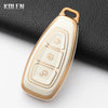 A white silicone car key fob cover with gold accents resting on a black surface.