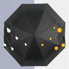 A black, geometric folding parasol decorated with white and yellow sun motifs.