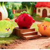 A set of hand-painted resin vegetable figurines, including a red tomato, yellow squash, and green lettuce, displayed in a gar