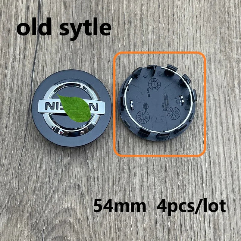A set of four black wheel center hub caps for Nissan models shown on a wooden surface.