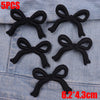 Five black fabric bows are displayed on a denim fabric surface.