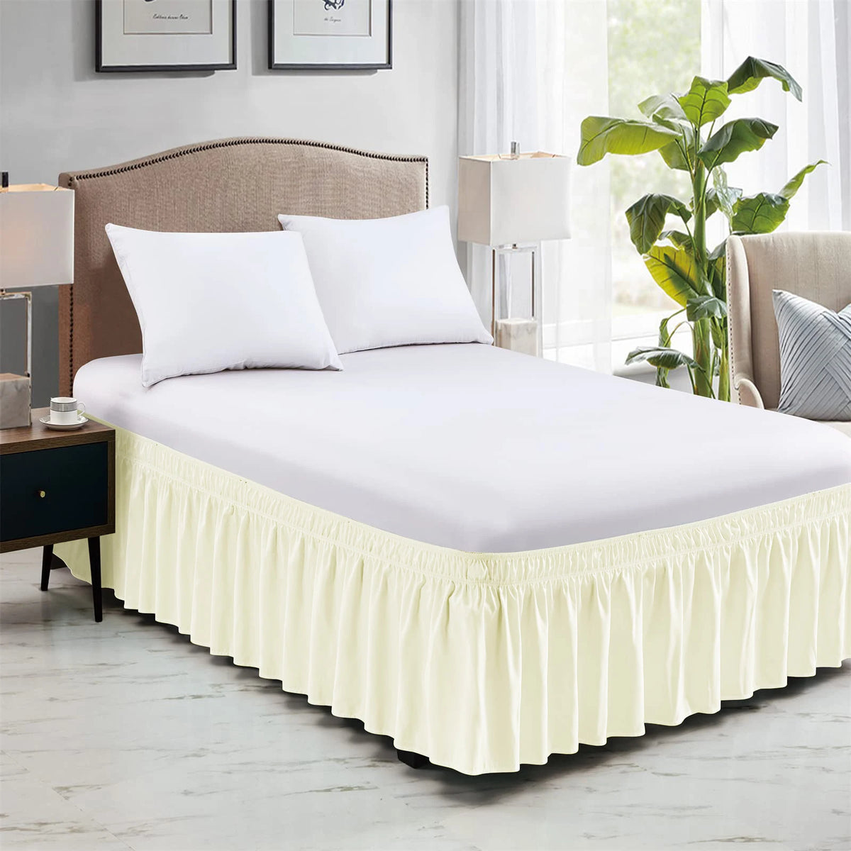 A white bed with a ruffled cream-colored elastic wrap-around skirt and white pillows in a bedroom setting.