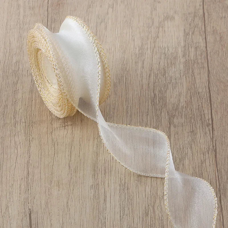 A roll of sheer, cream-colored organza ribbon with a wavy edge lying on a wooden surface.