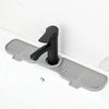 A black silicone sink faucet mat with a rotatable splash guard mounted on a white countertop.