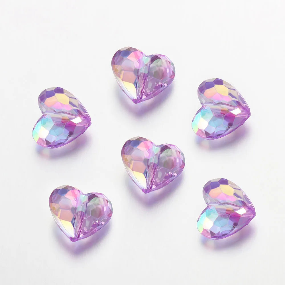 Twenty clear pink acrylic heart beads scattered on a white background.