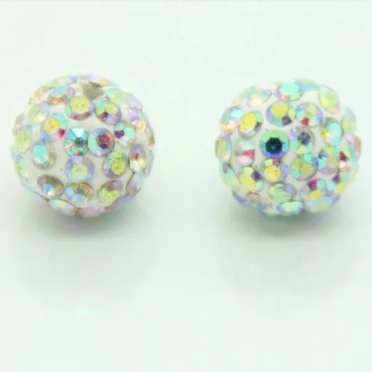 Two spherical beads covered in iridescent glitter and small colored stones for DIY jewelry making