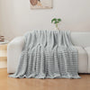A light gray soft and cozy brushed flannel throw blanket draped over a white sofa.