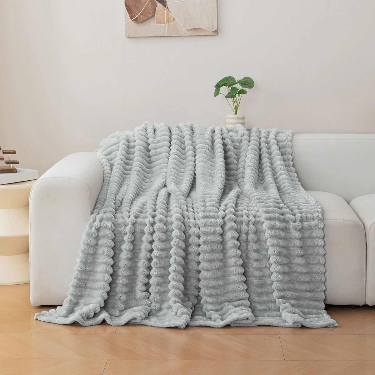 A light gray soft and cozy brushed flannel throw blanket draped over a white sofa.