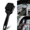 A black heavy-duty tire and wheel cleaning brush set being used to clean a car wheel.
