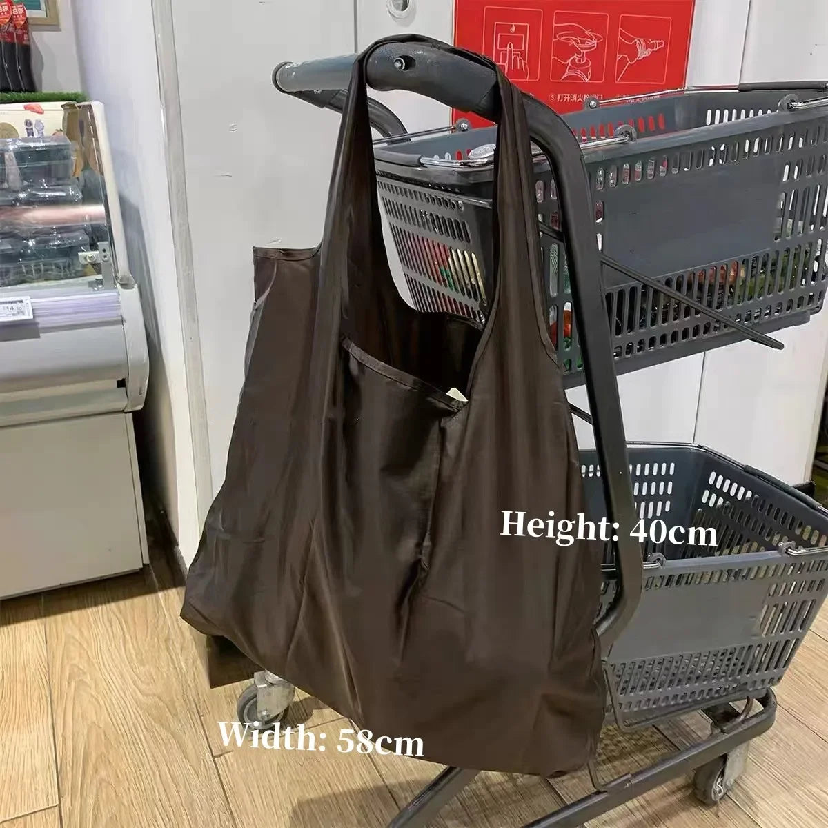 A brown foldable nylon shopping tote bag is shown hanging on a wire shopping cart.
