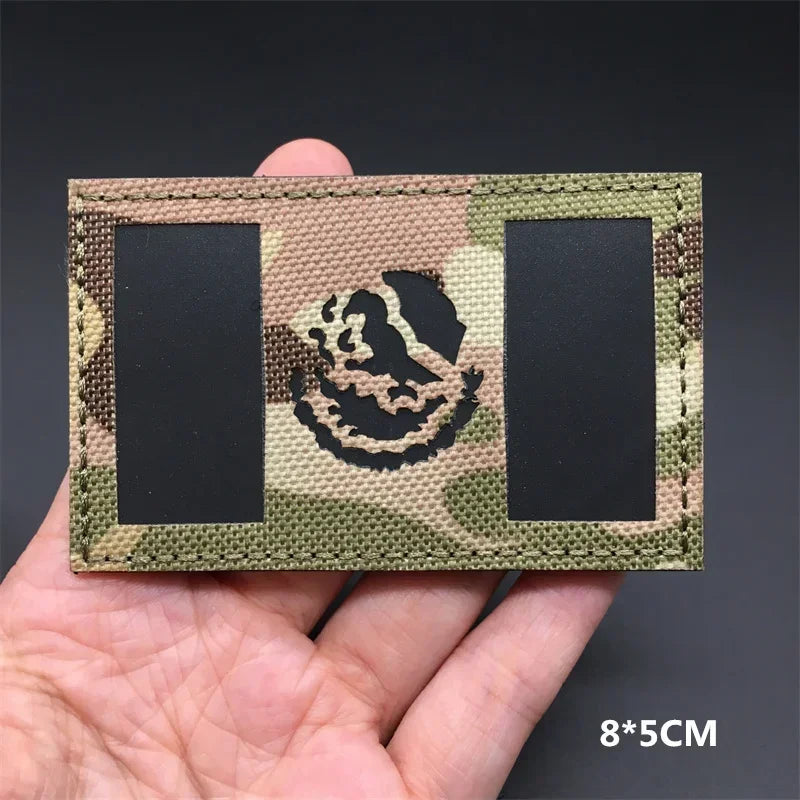 A close-up of a rectangular tactical patch featuring a camouflage pattern and an embroidered national flag design.