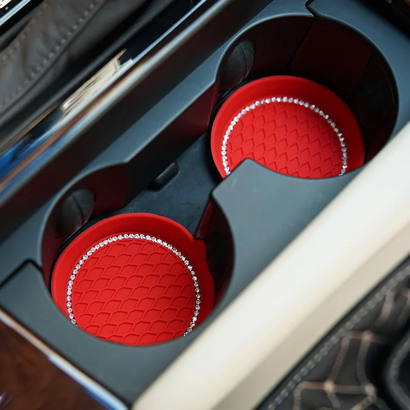 Red silicone cup holder coasters with rhinestone trim inside a dark car console.