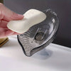 A hand holds a white self-draining soap dish with a suction cup design.