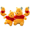 A set of three yellow Winnie the Pooh plush toys wearing red shirts.