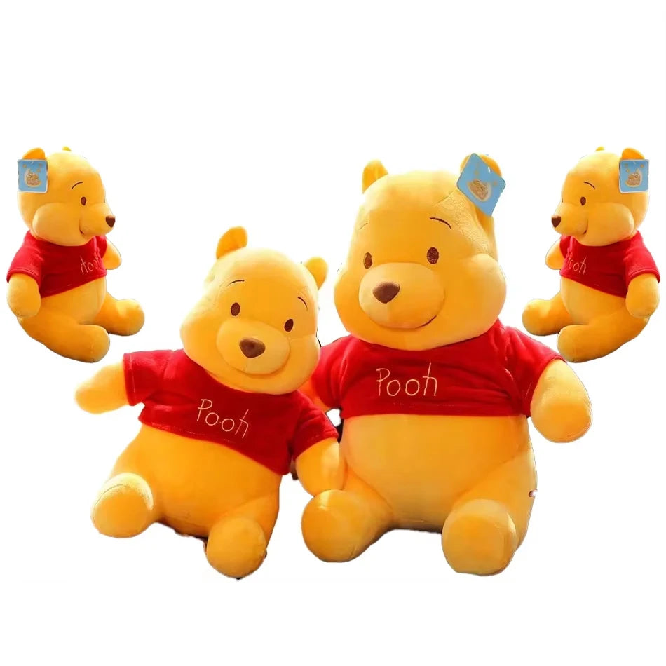 A set of three yellow Winnie the Pooh plush toys wearing red shirts.