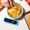 A hand holds a glow-in-the-dark silicone TV remote cover with a lanyard next to tortilla chips.
