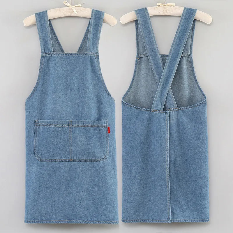 A light blue denim cross-back apron displayed on a hanger.
