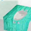 A green disposable toilet seat cover is shown, folded and ready for use.